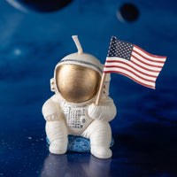 Close-up of Southlake Gifts Astronaut Landing Candle holding a U.S. flag, an unlit handmade astronaut candle with detailed spacesuit design, ideal for space party décor and gifting.
