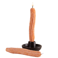 Front View of the Southlake Gifts Churros food Taper Candle set is lit with white background showcasing one churro taper candle in the candle holder, and the other churro taper candle is lying on the ground.