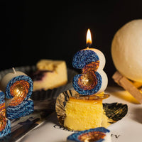 Southlake Gifts Galaxy black hole number candles displayed around cheesecake dessert with a lit number 3 candle as a birthday cake topper, space themed novelty candles for a cosmic celebration.