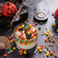 Top view of Halloween wax melts colorful spooky mix 6 oz unscented in candle jar surrounded by pumpkins and skeleton décor