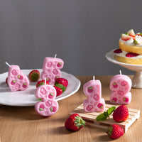 Southlake Gifts set of pink strawberry number candles from one to five displayed on a table, each featuring engraved strawberries. Cute handmade number candle cake toppers and birthday décor for girls.