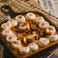 Close-up of Southlake Gifts Skillet S’mores Candle with melted wax resembling toasted marshmallows and melted chocolate, a hyper realistic dessert candle with multiple cotton wicks inside a skillet pan, a creative handmade food candle and unique foodie gift for birthdays, holidays, and housewarming gifts.