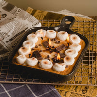 Southlake Gifts Skillet S’mores Chocolate and Marshmallow Candle burning inside a real skillet pan, featuring toasted marshmallows, chocolate bars, and chocolate chips on a cookie base, a handmade dessert candle inspired by classic campfire s’mores and a fun novelty candle gift for foodies and candle lovers.