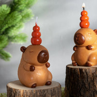 Two Southlake Gifts handmade Capybara Candles are lit, fruity scented hand-painted animal candle featuring stacked orange topper inspired by Japanese hot-spring capybaras