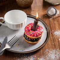 Overhead view of Southlake Gifts doughnut candle while lit up, chocolate-scented handmade food candle with sprinkles. Unique centerpiece and novelty décor gift.