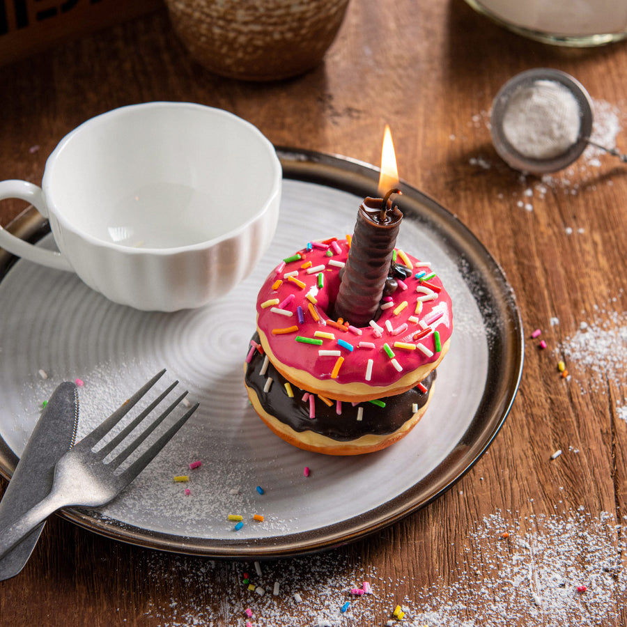 Overhead view of Southlake Gifts doughnut candle while lit up, chocolate-scented handmade food candle with sprinkles. Unique centerpiece and novelty décor gift.