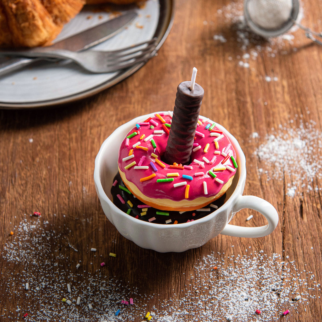 Handmade doughnut candle styled in teacup, realistic food candle design with frosting, sprinkles, and chocolate stick wick. Playful dessert-inspired décor.