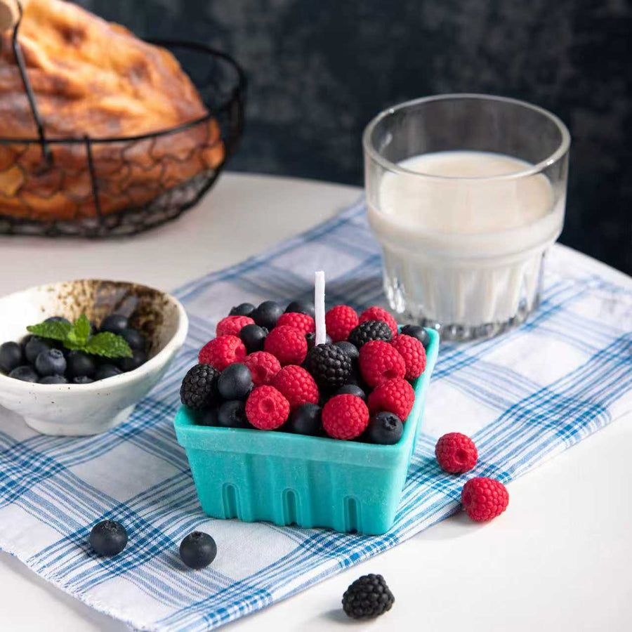 Handmade Southlake Gifts Berry Basket Candle with lifelike blueberry, raspberry, and blackberry wax melts arranged in a teal wax basket beside milk and pastries — a realistic fruit candle ideal for gifting and home decoration.