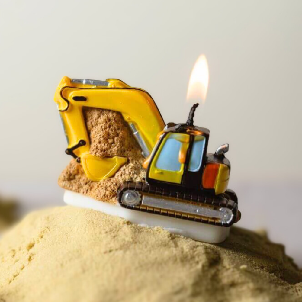 Southlake Gifts Excavator Candle displayed lit on sand, a handmade construction-themed candle cake topper that mimics a real excavator, a playful party favor and thoughtful gift for construction birthday celebrations.