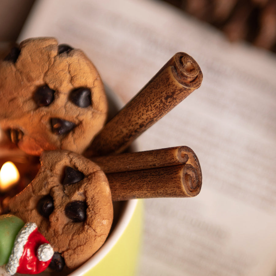 Close up look at the Cinnamon sticks candle wax melt and Chocolate Chip cookies wax melts sitting inside the  holiday cocoa candle mug — handcrafted by Southlake Gifts for realistic food candle. 