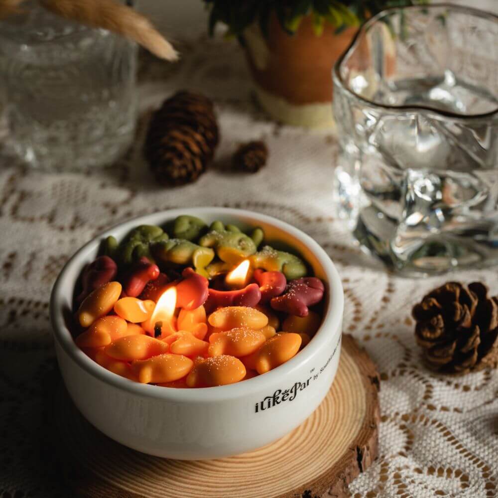 Lit Fish & Crackers Candle Bowl from Southlake Gifts glowing on a lace table, handcrafted soy candle with colorful wax fish melts, a playful handmade gift for cozy décor fans.
