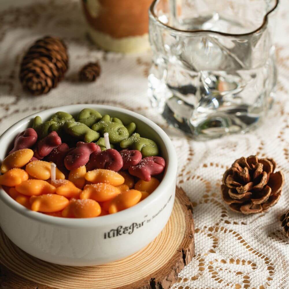 Southlake Gifts Fish & Crackers Scented Candle placed on wooden coaster with pinecones and glass cup, handmade novelty décor candle that makes a fun seasonal gift.