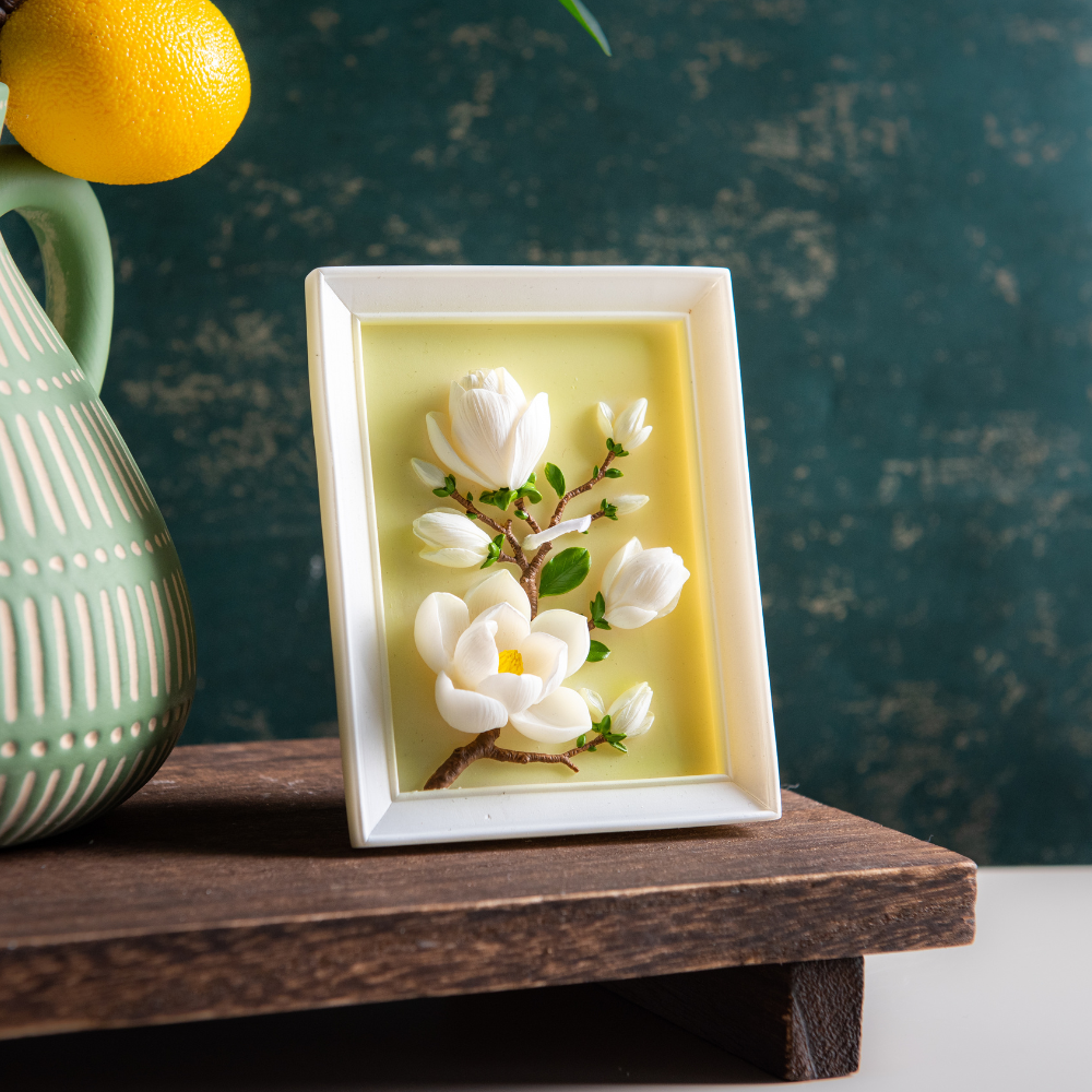 Southlake Gifts magnolia frame candle standing vertically on a shelf, showcasing a hand-carved botanical magnolia design within a sculptural picture frame candle, a unique handmade soy candle perfect for elegant décor and meaningful gifting.