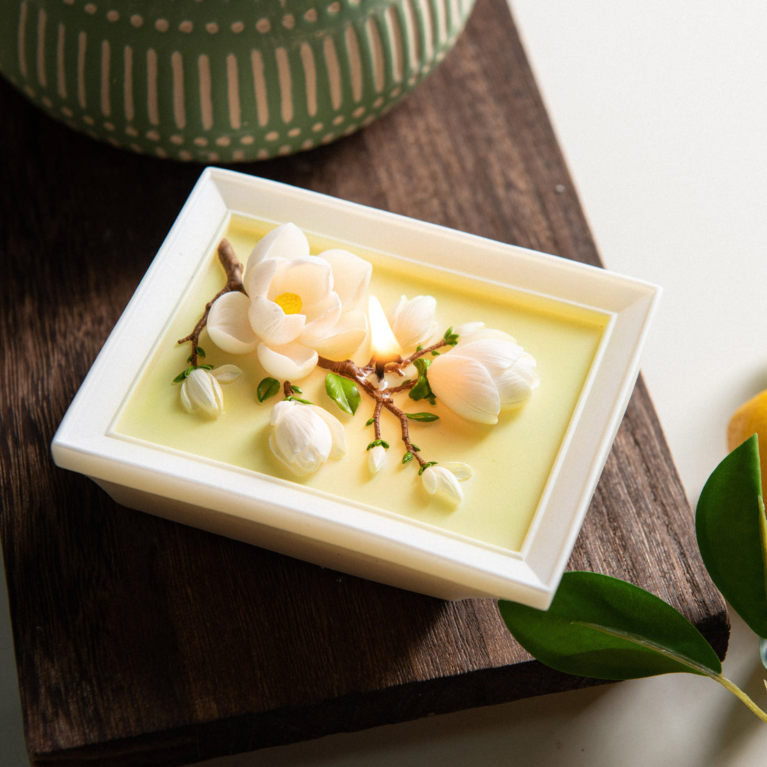 Close-up of Southlake Gifts Framed Magnolia Bloom Candle laid flat, revealing layered magnolia petals and branches embedded in soy wax, a botanical art candle designed as decorative home décor and an elevated gift for special occasions.