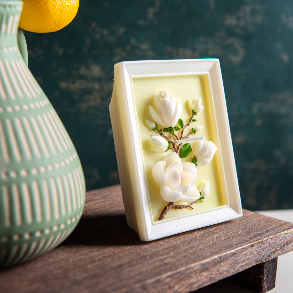 Southlake Gifts framed magnolia candle styled on a wooden surface with home décor accents, combining botanical floral sculpture and picture-frame candle form, a handmade scented candle ideal for gifting, housewarmings, or elegant interiors.