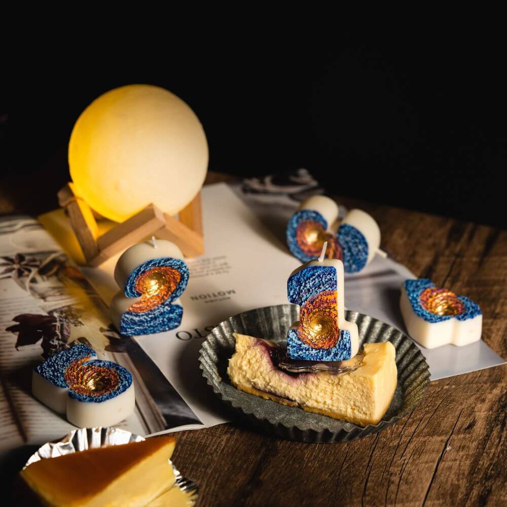 Southlake Gifts galaxy black hole number candle styled on cheesecake dessert with space themed décor and glowing moon lamp, a handmade novelty birthday candle perfect as a cake topper and a unique gift for space lovers.