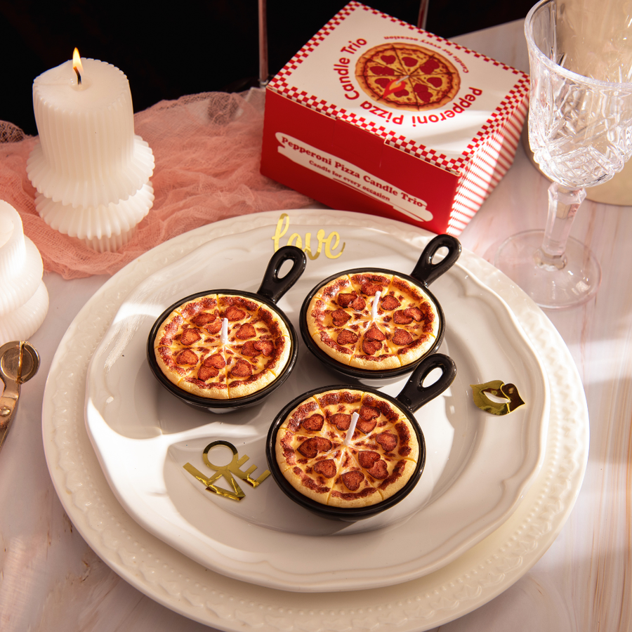 Southlake Gifts Heart Pepperoni Mini Pizza Candle Trio displayed on a decorative plate with its gift-ready packaging behind it, featuring three realistic mini pepperoni food candles in reusable skillets. A unique novelty candle set perfect for gifting and home décor.