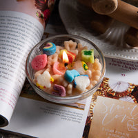 Close-up of one Cereal Charm Candle from Southlake Gifts surrounded by white hydrangeas, showing its realistic cereal wax melts in bright rainbow colors — a handmade candle that makes a thoughtful gift for any season.