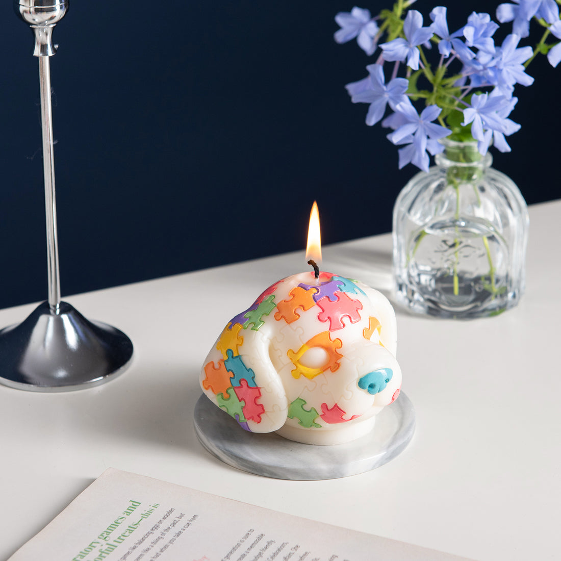 Southlake Gifts Puzzle Pup Candle is lit up in a side angle – scented pine dog-shaped candle on tabletop, unique handmade puzzle piece décor