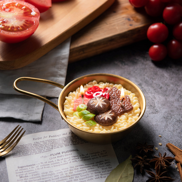 Southlake Gifts handmade Ramen Noodle Candle in golden pot with wax noodles, beef, mushroom, scallion, carrot, and chili toppings. Realistic food candle décor.