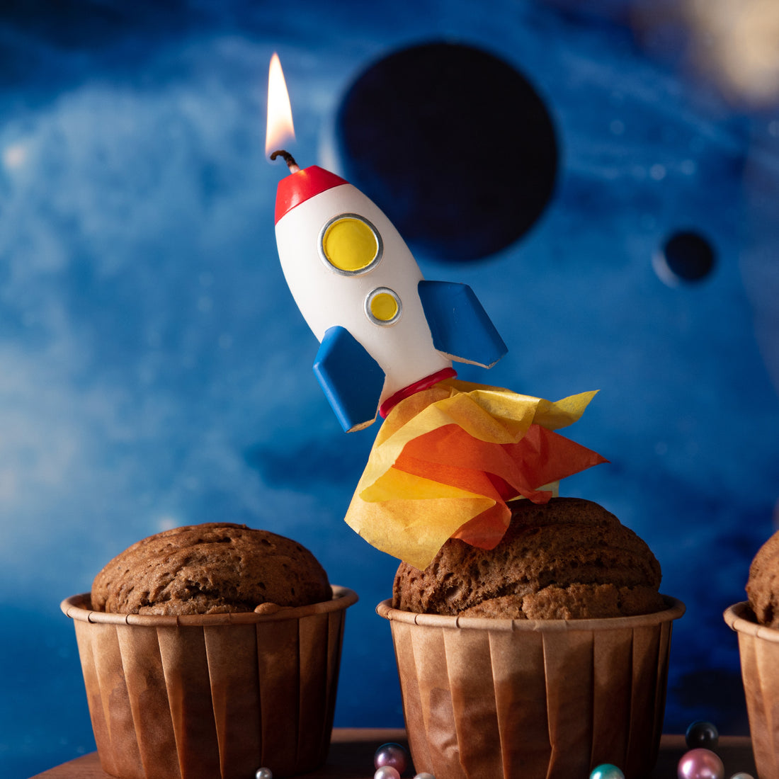Southlake Gifts Rocket Launch Candle lit atop a cupcake with flame detail, a handmade space-themed cake topper candle designed for birthday celebrations and imaginative cake decoration.