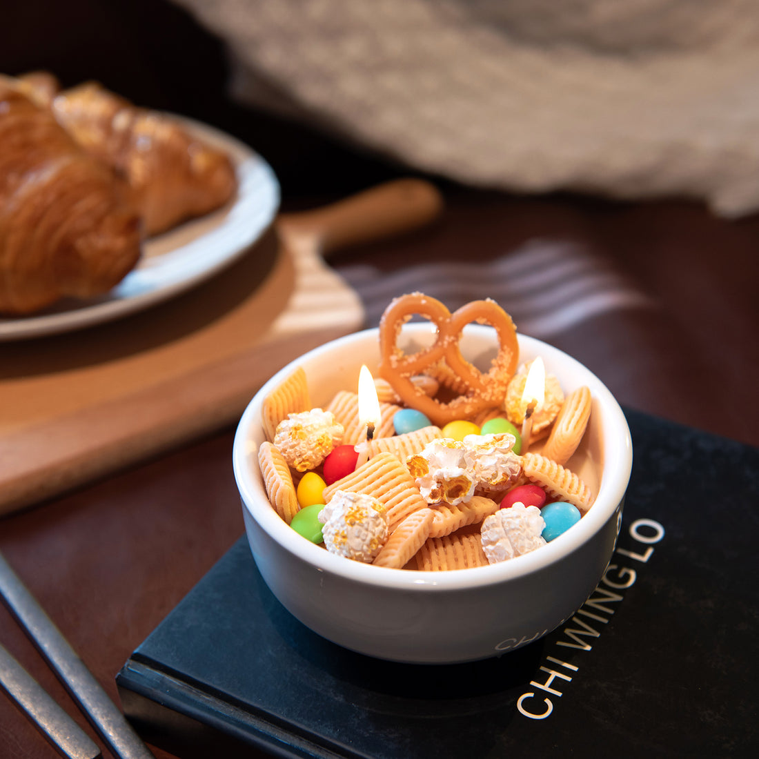 Southlake Gifts handmade Snacks Candle Bowl styled on a coffee table atop a book, featuring realistic snack-shaped wax pieces in a ceramic bowl, a playful yet refined home décor candle that makes a thoughtful gift for any season.