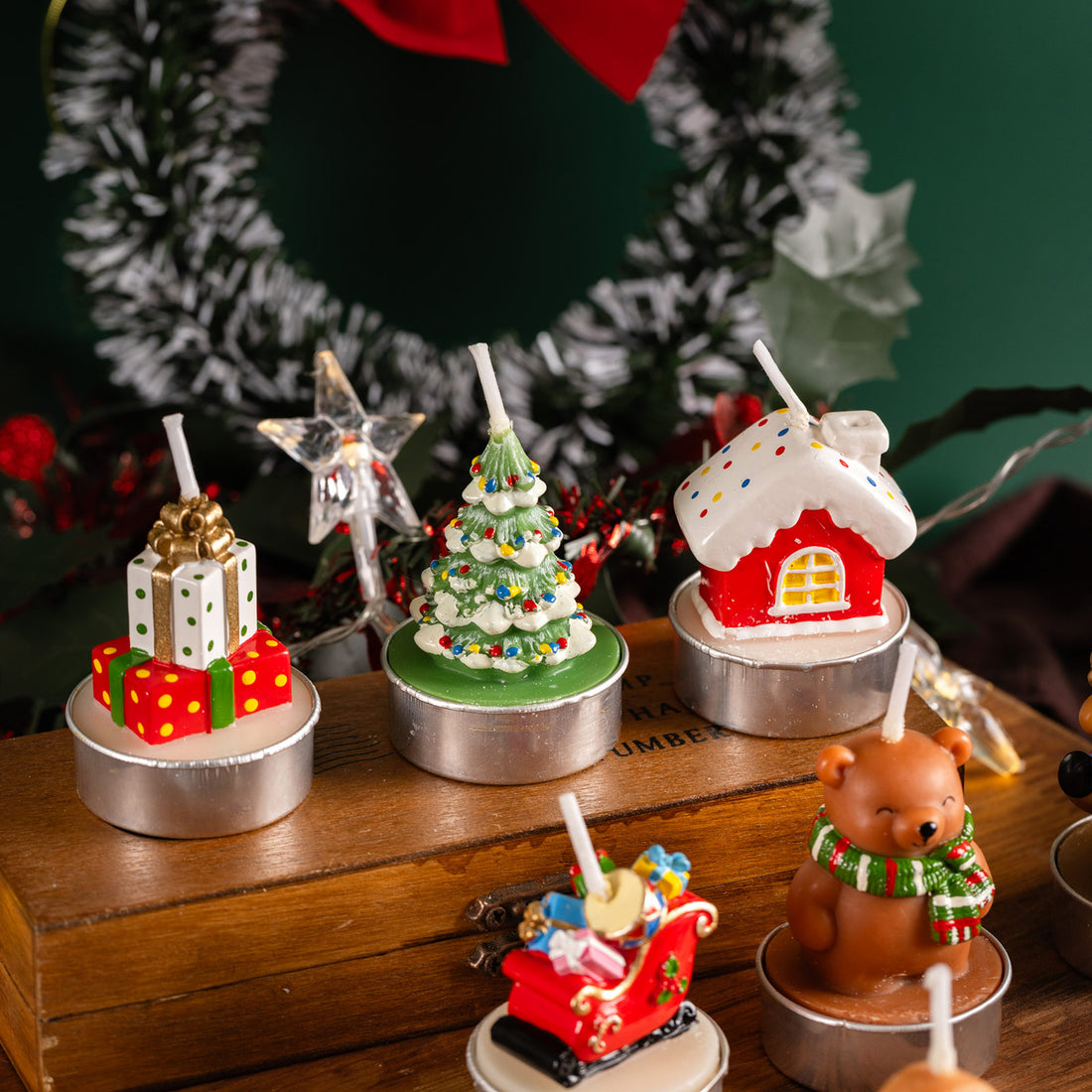 Close-up of Christmas tree, gift box, and gingerbread house candles arranged on wooden surface, perfect artisan décor pieces for home styling and gift giving.
