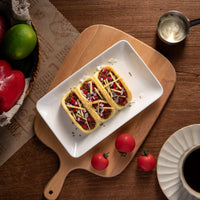 Overhead shot of three Southlake Gifts lemon-scented taco candles displayed on wooden board beside tomatoes and coffee cup, handmade novelty gift candle décor.