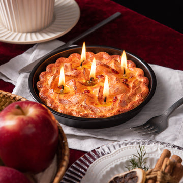 Southlake Gifts Apple Pie Candle is lit up– realistic dessert-inspired food candle with lattice crust and five glowing wicks on black baking pan.
