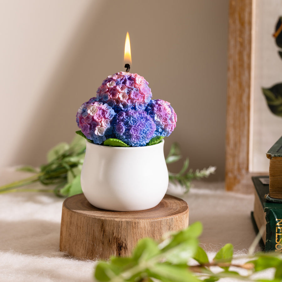 Southlake Gifts Hydrangea Candle lit in a white ceramic pot, showcasing hand-painted purple and blue petals with lifelike floral texture — a handmade scented candle that makes a thoughtful gift for home décor lovers.