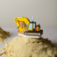 Southlake Gifts Excavator Candle displayed on sand, a handmade construction-themed candle cake topper designed to resemble a real excavator, a playful gift for construction birthday celebrations.