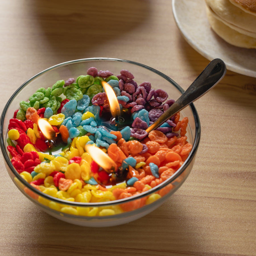 Close-up of the Fruity Pebbles Candle lit with three glowing wicks among rainbow wax cereal pieces — a vibrant handmade food candle that makes a whimsical gift for any candle lover.