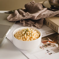Handmade Macaroni & Cheese Pasta Candle by Southlake Gifts displayed on a cozy table with fabric and books — realistic pasta-shaped wax candle with buttery cheese aroma, a perfect novelty gift for holidays and home décor.