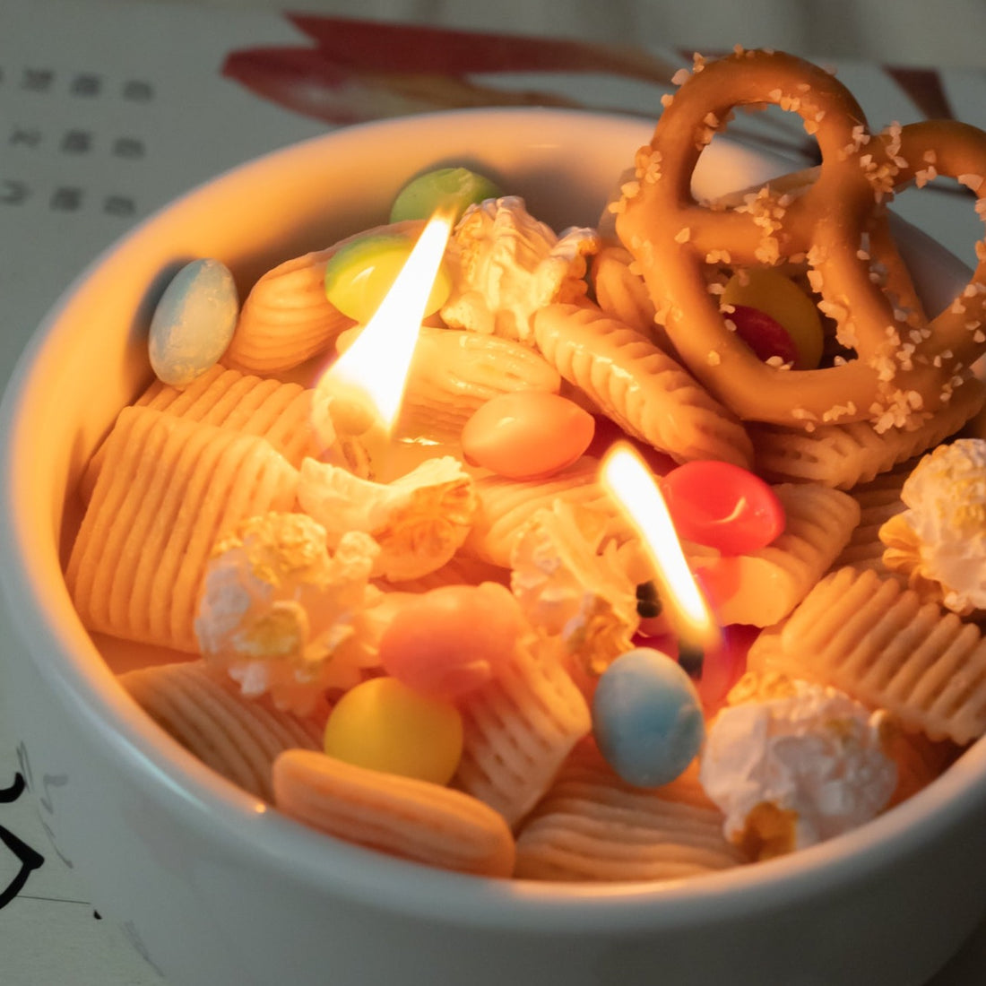 Close-up of lit Snacks Bowl Candle revealing melted popcorn and candy-shaped wax pieces — a realistic handmade candle ideal for gifting during holidays or birthdays.
