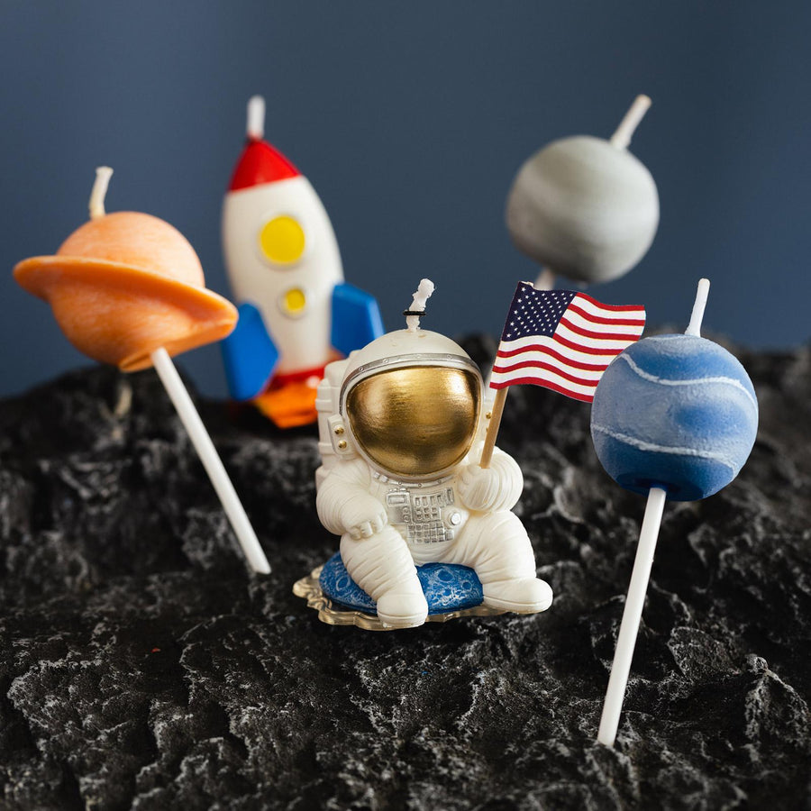 A spaceman holding a US Flag with a rocket and three planets on it.